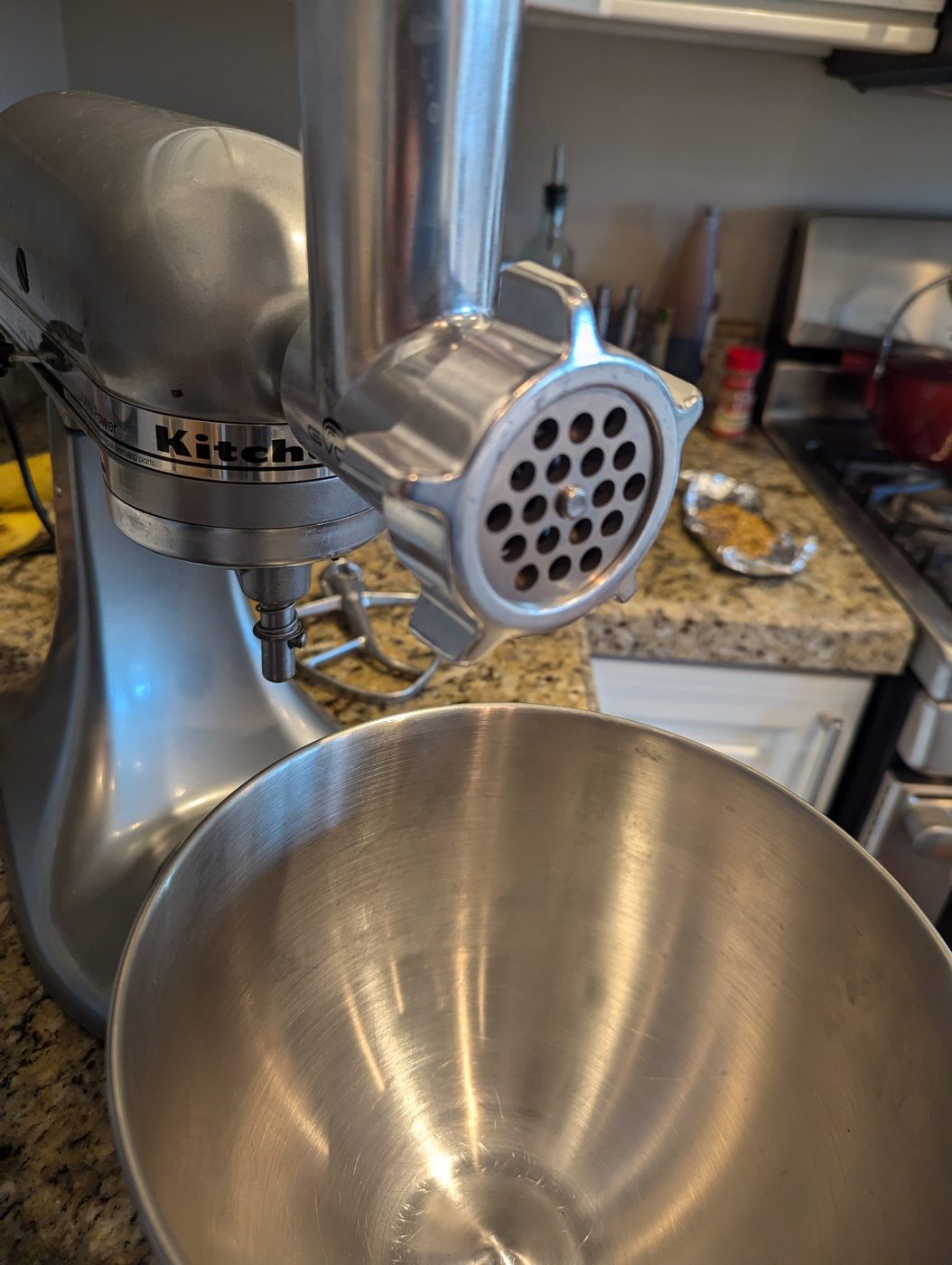 A KitchenAid meat-grinder attachment fitted with a coarse grinding plate