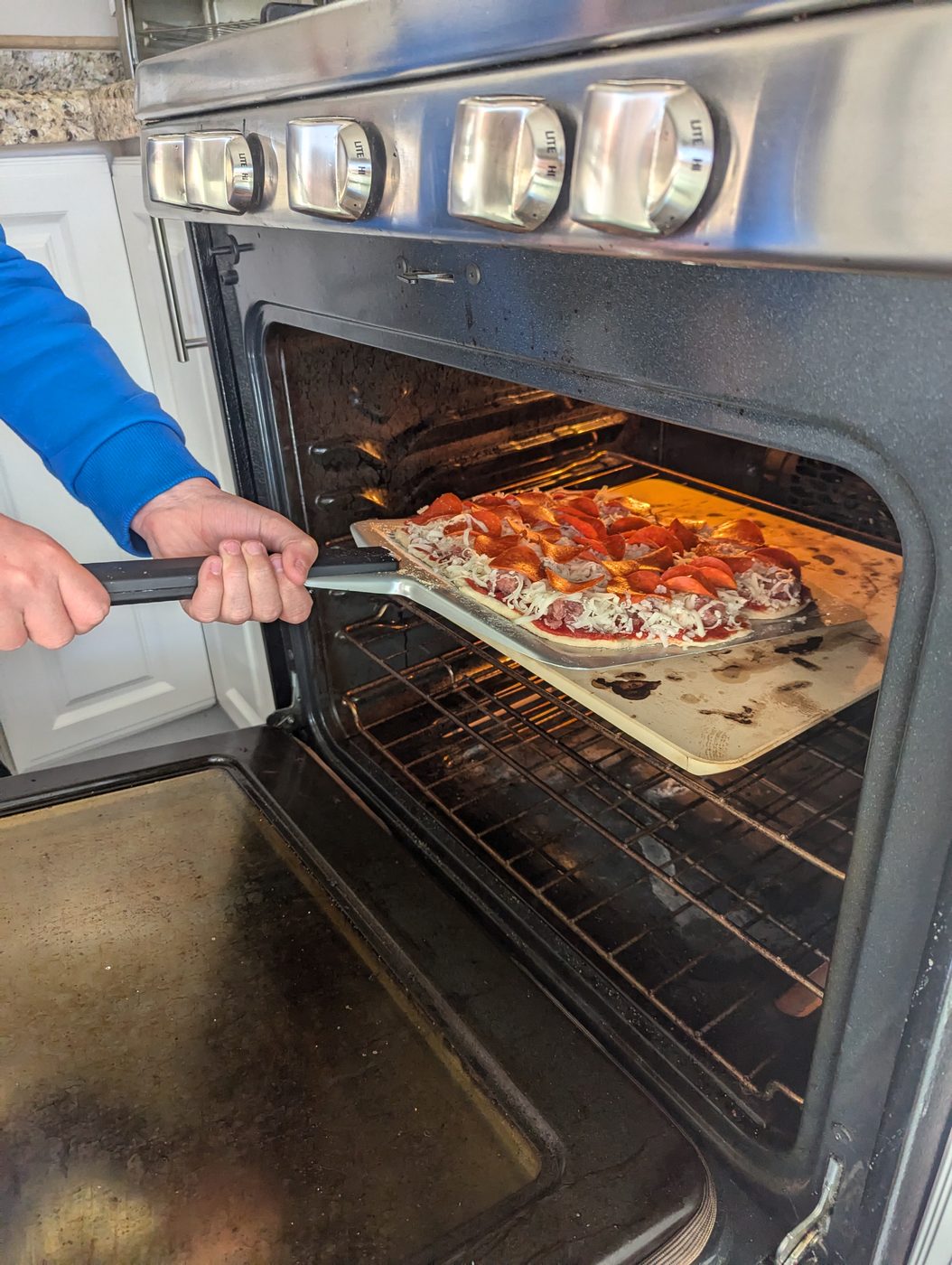 Pizza on a peel being slid into a 500-degree home oven
